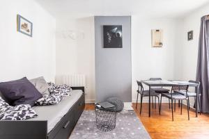 ein Wohnzimmer mit einem Sofa und einem Tisch in der Unterkunft Le Grey Cocon - Studio cosy aux portes de Paris in Saint-Mandé