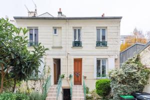 ein weißes Haus mit einer roten Tür und einer Treppe in der Unterkunft Le Grey Cocon - Studio cosy aux portes de Paris in Saint-Mandé