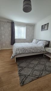 a bedroom with a bed with a rug and a window at Spacious 2 bedroom 2 Bathroom Flat in Hatfield near Hertfordshire University with Private Car Park Sleeps 5-6 in Hatfield