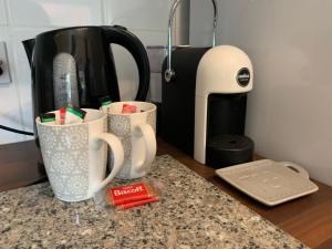 a counter top with two coffee cups and a toaster at Beautifully Styled 2BR Home with Garden in Manchester