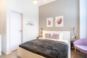ein Schlafzimmer mit einem Bett und einem rosa Stuhl in der Unterkunft Extreme Central - Modern Mini Studio in Budapest
