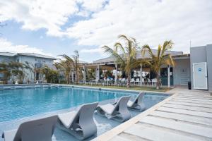 a swimming pool with lounge chairs next to a building at Olas del Mar by Playa Caracol Residences in Punta Chame