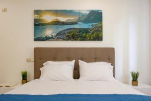 a bed with white pillows and a painting on the wall at Casa do Simão Gaula in Santa Cruz