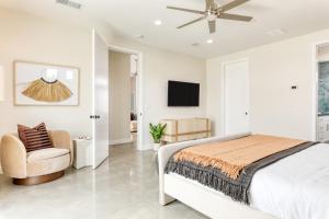 a white bedroom with a bed and a chair at Ishan by AvantStay Designer Joshua Tree Oasis in Yucca Valley