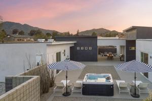 a patio with two umbrellas and a hot tub at Ishan by AvantStay Designer Joshua Tree Oasis in Yucca Valley