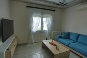 een woonkamer met een blauwe bank en een tv bij Villa Alexandra in Elevtheraí