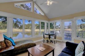 uma sala de estar com muitas janelas e uma mesa em 15 Lake Village by AvantStay Golf Course Lagoon Views em Isle of Palms