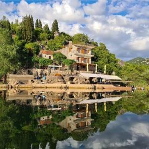 a house on a hill with a reflection in the water at Sunny Terraces in Cetinje
