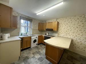 a kitchen with wooden cabinets and a white dishwasher at 80's Grandma London Experience ! in London