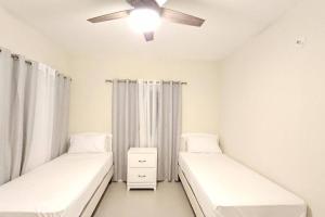 two beds in a room with a ceiling fan at Casa Fortuna in Lucea, Hanover in Point