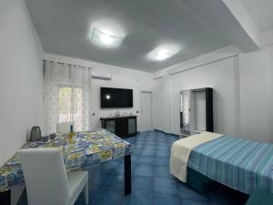 a room with a bed and a table and a television at CASA VACANZA IMPARO Ischia in Ischia Town