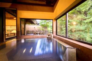 an indoor swimming pool in a house with large windows at Satonoyu Waraku 13 years or older in Minamioguni