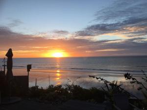 puesta de sol en la playa con puesta de sol en Absolute Beachfront Luxury Accommodation, en Paraparaumu