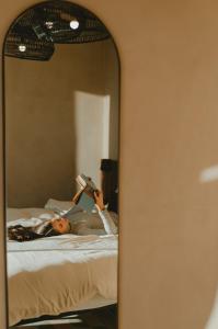 uma mulher deitada numa cama a ler um livro no espelho em Equ Hotel de Tierra em El Porvenir
