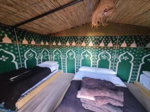 梅爾祖卡的住宿－Acacia Desert Camp，配有两张绿色和白色壁纸的客房内的床铺
