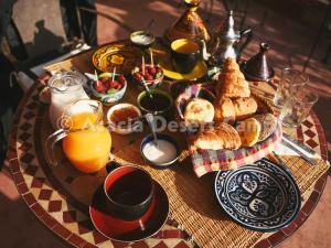 a table with breakfast foods and orange juice on it at Acacia Desert Camp in Merzouga