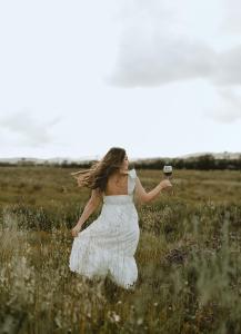 una donna in un campo con un bicchiere di vino di Equ Hotel Boutique a El Porvenir