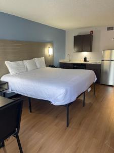 a large bed in a hotel room with a kitchen at Suburban Studios in Cordele