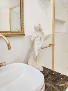 Eine Statue einer Frau, die neben einer Toilette im Bad steht. in der Unterkunft Arena and Opera Love - Historic House Amorino at "Palazzo Tiolo" Palace in Verona