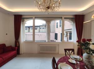 ein Wohnzimmer mit einem roten Sofa und einem großen Fenster in der Unterkunft Arena and Opera Love - Historic House Amorino at "Palazzo Tiolo" Palace in Verona