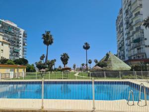 een groot zwembad met palmbomen en gebouwen bij Coqueto Estudio en Los Maites in Benalmádena