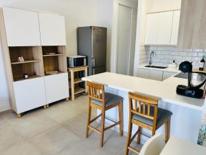 a kitchen with a counter and two chairs and a refrigerator at Pambnb - Modern Beachfront Apartment Hideaway in Santa Cruz de Tenerife