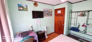 1 dormitorio con 1 cama y TV en la pared en Yellow House, en Coco