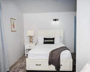 a bedroom with a white bed with a black pillow on it at Villa 409C in Jolly Harbour