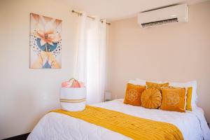 een slaapkamer met een bed met oranje kussens bij Sunset Harmony, Your Escape at Playa Hermosa in Sardinal