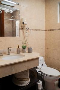 a bathroom with a sink and a toilet and a mirror at Sunset Harmony, Your Escape at Playa Hermosa in Sardinal