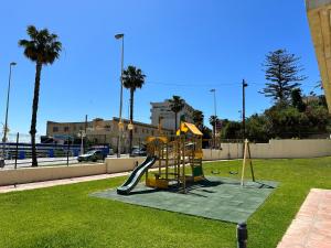 a playground with a slide in a park with palm trees at Aloha Playa Sol y Mar in Benalmádena