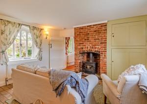 a living room with a couch and a fireplace at Gardeners Cottage in Bealings