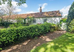 una casa bianca con una siepe davanti di Gardeners Cottage a Bealings