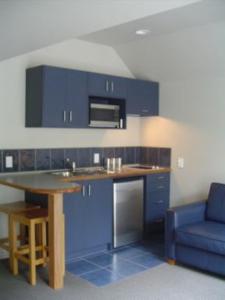 a kitchen with blue cabinets and a blue couch at Heriot Lane City Apartments in Dunedin