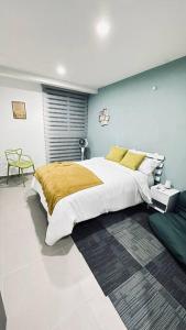een slaapkamer met een groot bed en een groene stoel bij Departamento al sur de la ciudad in Guadalajara