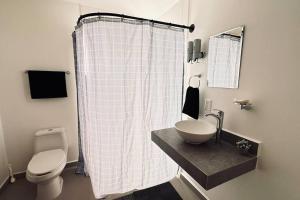 uma casa de banho com uma cortina de chuveiro branca e um WC. em Departamento al sur de la ciudad em Guadalajara