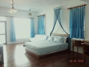 1 dormitorio con 1 cama con cortinas azules y escritorio en Ocean Sky B&B, en Huxi