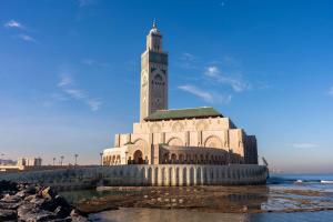 ein großes Gebäude mit einem Uhrturm am Strand in der Unterkunft Radisson Hotel Casablanca Gauthier La Citadelle in Casablanca