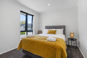 a bedroom with a large bed with a yellow blanket at Havelock Holiday House in Havelock North