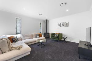 a white living room with a couch and a tv at Havelock Holiday House in Havelock North