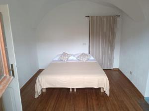 a bedroom with a bed with white sheets and wooden floors at Casa di Alvise in Lauco