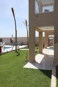 Luxurious & panoramic views في مراكش: منزل به ساحة بها عشب ونخل