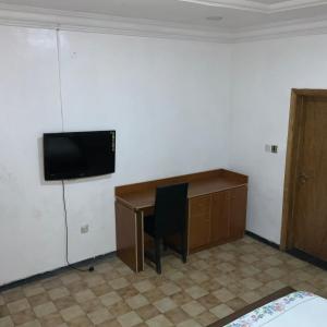 a room with a desk and a television on a wall at BLUE MOON HOTELS VICTORIA ISLAND in Lagos