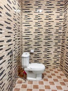uma casa de banho com um WC branco num quarto em azulejo em Adnan Lodge em Tamale