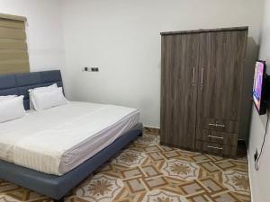 1 dormitorio con 1 cama y armario de madera en Adnan Lodge, en Tamale