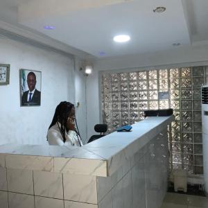 a woman sitting at a counter in a room with wine bottles at BLUE MOON HOTELS VICTORIA ISLAND in Lagos