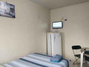 a room with a refrigerator and a tv on the wall at Residencial Andréa House in Manaus