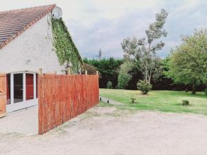 ein Haus mit einem orangenen Zaun neben einem Hof in der Unterkunft Home Gãyatri in Angé