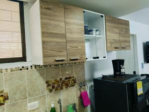 a kitchen with wooden cabinets and a refrigerator at Suite Hermosa ven descansa o trabaja El Rodadero Santa Marta in Gaira