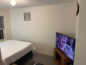 1 dormitorio con 1 cama y TV de pantalla plana en Comfort Queen, en Oshawa